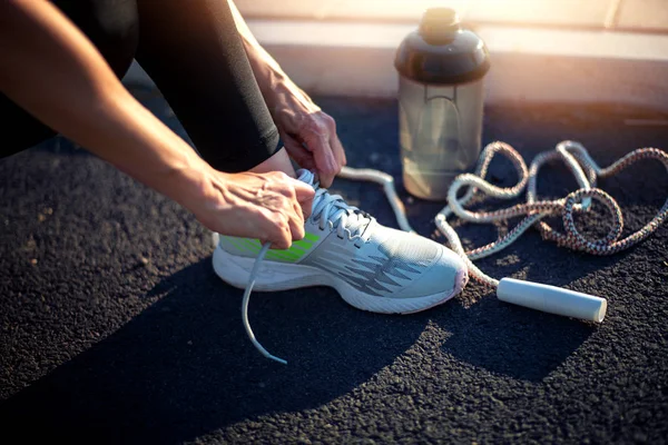 Close up, fitness woman tying shoelace.
