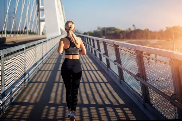 Adult fitness woman jogging on bridge. — Stock Photo, Image