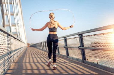 Yetişkin bir kadın köprüde ip atlıyor..