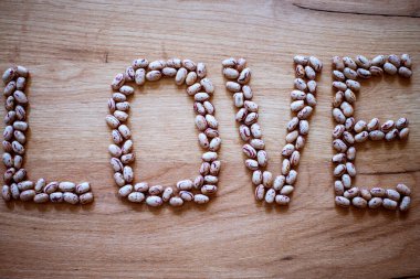 Aşk kelimesi evdeki ahşap bir masada fasulyeyle yazılmış..