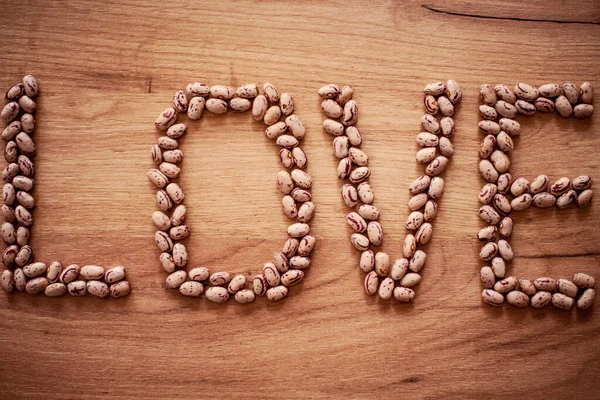 Aşk kelimesi evdeki ahşap bir masada fasulyeyle yazılmış..