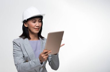 Güzel Asyalı Akıllı Mimarlar 50 'li yaşlarda, 60' lı yaşlarda, beyaz kasklı kadın elinde tablet, portre stüdyosu gri arka plan fotokopi alanını aydınlatıyor. Yaşlanan toplum kadınlarının yapabileceği konsept.