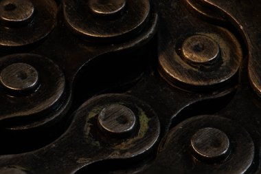Metal zincir siyah kumaş üzerinde daire oluşturur, makro istifleme fotoğrafçılığını kapatır, koyu renge maruz kalır