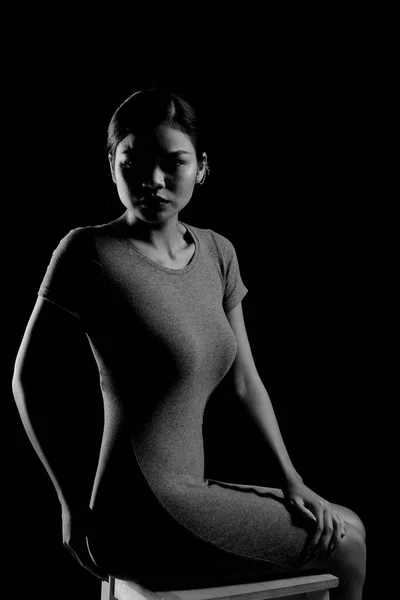 Asian Woman practice yoga and meditation with stretching arms, legs and knees, lady sit on floor to balance calm mindset, wear black dress in black and white monochrome concept