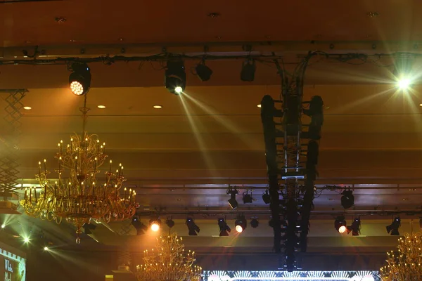 Par Lights beams Spotlight ray moving lighting blinking on rack construction to chandelier in Hotel Ballroom