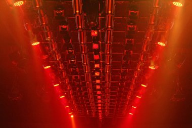 Sahne rampasında, kırmızı renkte, inşaat ışınları üzerinde ışık saçan performanslar.