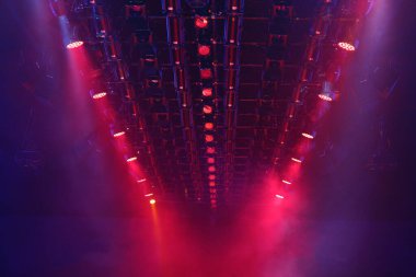 Sahne rampasında, kırmızı renkte, inşaat ışınları üzerinde ışık saçan performanslar.