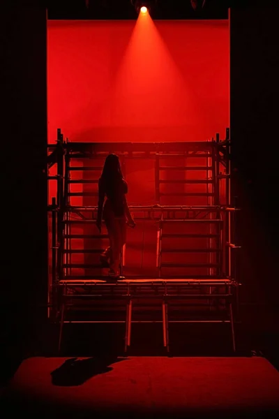 Red Backgrounds of Model walk on Metal stair construction as Runway for Fashion Show to start with silhouette no face then catwalk will present new collection on normal color