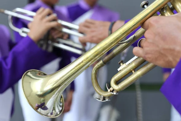 Details form a Show and Marchingband, Uniforms and Instruments. Old age used Trumpet in school band hand with purple uniform blur background