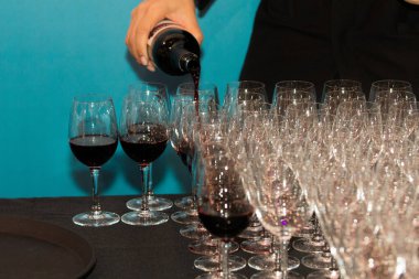 Pek çok boş şarap kadehi sıralı ve cam zemin gibi sarı arka plan ışığı, barmen şarap şişeden şarap kadehine VIP için sanırım parti var