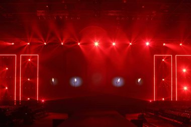 Moda Şovu Sahnesi Kızılımsı atmosferde dumanlı, spot ışığı kırmızı renkte, ölüm döşeğinde, inşaat alanında siyah yürüyüş yolu ve boş koltuklu kamera kulesi rayı, kopyalama alanı