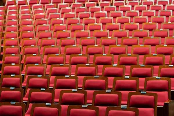 大礼堂剧场音乐会或研讨会大堂设有天花板照明的多排椅子座位上有木制框架的红色聚氨酯皮革网状布 — 图库照片