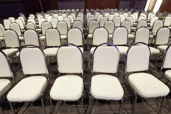 Many White PU Chairs arranged in row order for Performance Contest in Ballroom Hotel, Multiple Portable Seats set up for Conference meeting in Business Seminar of Company, Copy space for text logo