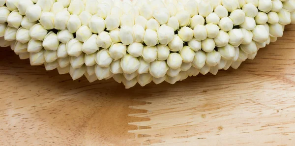 手のためのラウンド小さな花の形で白い花をオフに多くは 木製のテーブルの上に置く 一緒にタイトな手配開催テキストロゴのためのスタジオ照明白い背景コピースペース Malaiドックラックという名前 — ストック写真