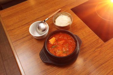 Restorandaki Kore yemeği ahşap masa, baharatlı pirinç keki, erişteli tofu sebzesi ve kırmızı sıcak çorba.