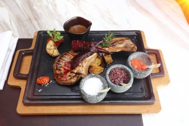 Üç çeşit tuz ve soslu domuz pirzolası, altında ahşap ısıtıcı, Amerikan tarzı lüks restuarant.