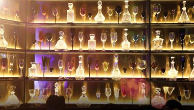 Birçoğu arka planda boş şişe ve şarap kadehi dekoratifi gösteriyor. Rafta, gece kulübünün arka tarafında. Arka planda ışık arka planında.