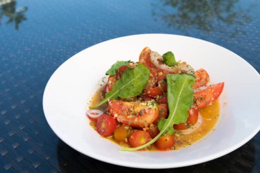 Yeşil yapraklı sebzeli marine edilmiş domates salatası, füzyon yemeği stili okyanus mangrov ağacı adası boyunca cam masaya dizilmiş, metin logosu için boş fotokopi alanı leziz