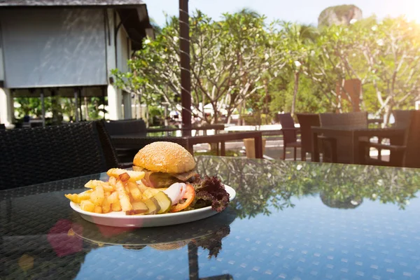 Chicken Beef Beacon Ham Cheese Burger with fried potato chip, Fusion food stylish arrange on glass table along ocean mangrove tree Island, empty copy space for text logo Yummy