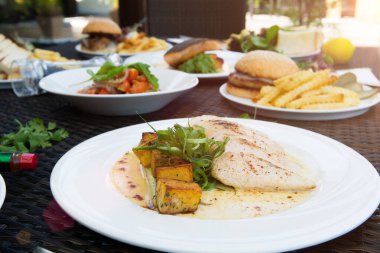 Karışık deniz ürünleri, spagetti, kulüp sandviçi, burger, salata, sıcak baharatlı yiyecekler tropikal okyanus atmosferinde, grup açılı kamera görüntülü öğle yemeği, arkadaşlarla aile yemeği.