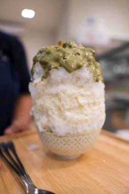 Yüksek Yeşil Çay Bingsu buzu, tatlı tatlı tatlı atmosferde bir sürü yemek tabağı ve restoranda insanlar, seçici odak bulanıklığı.