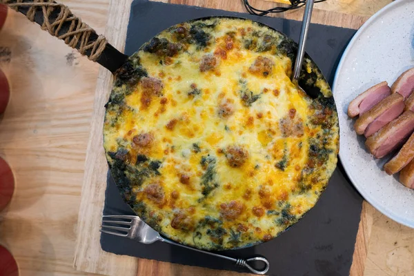 Spinach Lasagna with cheese on top round pan on wooden table, American Style BBQ grill on natural charcoal to make good smell