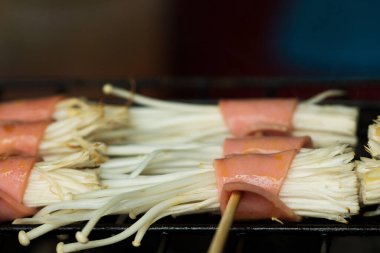 Kömür ve dumanlı eski moda fırında ızgara Bacon enoki mantarı. Asya 'da çok lezzetli ve pahalı görünen ünlü sokak yemekleri.