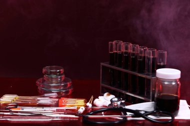 Cam Laboratuar Test Araçları Ekipmanları, Şırınga, steteskop, tepsi, gözlük, maske, çekim için hazırlan. Kırmız tonu yansıt duman arka planı, kopyala boşluk