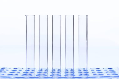 Mavi Plastik Şeffaf Stantta Cam Tüplü Boş Laboratuvar Grubu, Stüdyo beyaz arka plan aydınlatma, izole edilmiş kopya alanı, yakın çekim