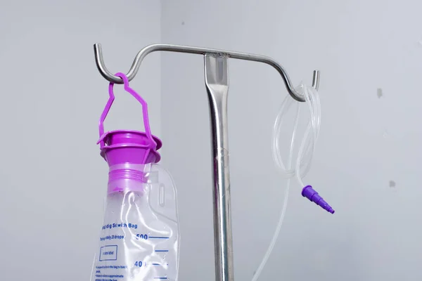 Feeding Pump medical device purple color to supplement nutrition liquid food to tube Enteral feeding fluid set bag with clamp hanging on stand.