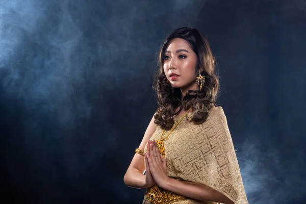 タイの伝統衣装の黄金のドレスや東南アジアの金は煙の肖像画とスタジオダークブラックの背景コピースペースの下に多くのポーズで装飾スタンドとアジアの女性のドレス — ストック写真