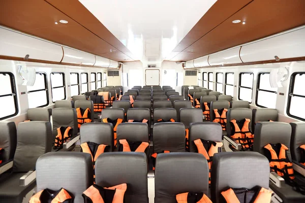Many Seats row inside luxury cruise ferry with orange life vest jackets for Tourist to use to swim in Ocean sea and snorkeling underwater trip and safety first during transport