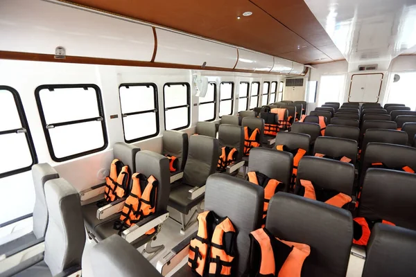 Many Seats row inside luxury cruise ferry with orange life vest jackets for Tourist to use to swim in Ocean sea and snorkeling underwater trip and safety first during transport