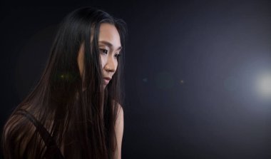 Sadece bronz tenli Asyalı kadın siyah düz saçlı arka plan, soyut düşük pozlama kontrast, metin logosu için fotokopi alanı, kırık kalp yalnız kız ağlayabilir.