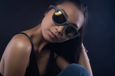 Beyaz Duman Bronzlaşmış Asyalı Kadın siyah siyah saçlı, güneş gözlüklü, koyu arkaplan, soyut düşük pozlama kontrast, metin logosu için kopya alanı, kırık kalp yalnız kız ağlayabilir