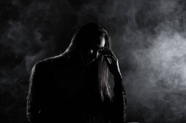 Beyaz dumanlı bronz tenli Asyalı kadın koyu arkaplanda yoğun kabarık tüylü sisli düz saçlı, soyut düşük pozlu kontrast, metin logosu için kopya alanı, kırık kalpli yalnız kız ağlayabilir.