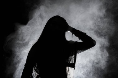 Beyaz dumanlı bronz tenli Asyalı kadın koyu arkaplanda yoğun kabarık tüylü sisli düz saçlı, soyut düşük pozlu kontrast, metin logosu için kopya alanı, kırık kalpli yalnız kız ağlayabilir.