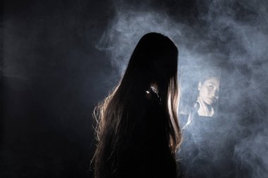 Beyaz dumanlı bronz tenli Asyalı kadın siyah düz saçlı, yüzü koyu arkaplan, soyut düşük pozlama kontrast, metin logosu için fotokopi alanı, kırık kalp yalnız kız ağlayabilir