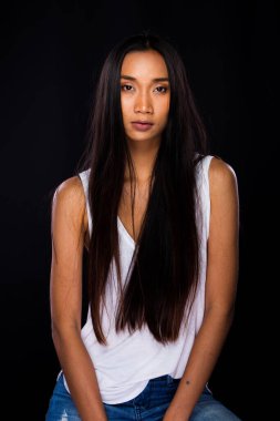 Güzel Asyalı Uzun düz siyah saçlı beyaz yelekli kadın ince giyimli, makyajlı, stüdyo ışıklandırmalı siyah arka plan fotokopi alanı