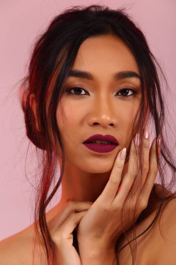 Güzel Asyalı Uzun düz siyah saçlı kadın ceket önleyici, makyaj malzemesi, stüdyo ışıkları pembe arka plan izole fotokopi alanı, dikey