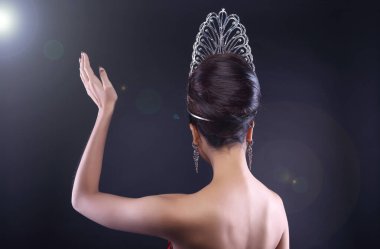 Back rear side view Portrait of Miss Pageant Beauty Contest in Red sequin Evening Gown with Diamond Crown wave hand, Asian Woman fashion make up hair style, studio lighting dark background copy space