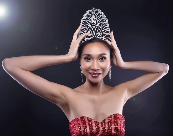 Portrait Miss Pageant Beauty Contest in Red sequin Evening Ball dress Diamond Crown, Asian Woman fashion make up face eyes heart black hair style, studio lighting dark background dramatic copy space