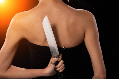 Asya 'lı Kadın' ın arkadan görünüşü, elinde keskin bir bıçak, stüdyo siyah arka planlar aydınlatıyor, bıçaklayarak ihanete hazır.