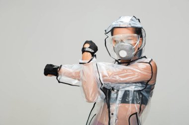 Asyalı bronz tenli spor kadın kol esnetme egzersizi spor sutyen eldiven şeffaf yağmurluk maske güvenlik gözlükleri stüdyo aydınlatma gri arka plan, gelecekteki kirlilik kavramı