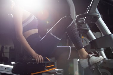 Spor salonunda spor bisikletli bisiklet itme makinesinde ısınan Asyalı zayıf spor kadın siyah saç sutyeni. Kavramsal kadın sporcu olabilir. Sağlıklı, sırt lambası olmadan.