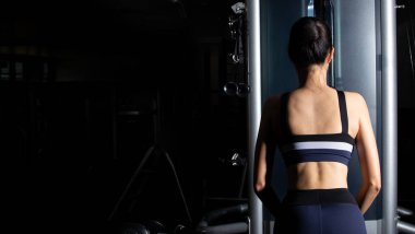 Arkadan bakıldığında, Asyalı ince spor kadın siyah saçlı spor sutyen, spor salonundaki kaslı kaslı kolları indir egzersizinde ısınıyor. Kavramsal kadın sporcu olabilir. Sağlıklı, kopyalama alanı.