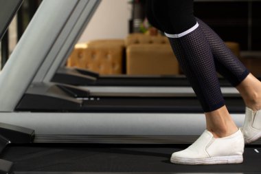 Slim Fitness kadınının beyaz ayakkabıları Fit Gym 'de koşu bandında ısınıyor. Kavramsal kadın sporcu olabilir. Sağlıklı, kopyalama alanı.