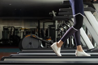 Slim Fitness kadınının beyaz ayakkabıları Fit Gym 'de koşu bandında ısınıyor. Kavramsal kadın sporcu olabilir. Sağlıklı, kopyalama alanı.