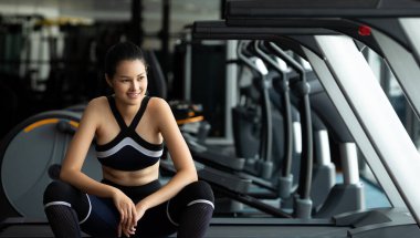 Asyalı ince spor kadın siyah saçlı spor sutyen beyaz ayakkabı egzersizi ısınıyor ve Fit Gym 'de koşu bandında yorgun oturuyor. Kavramsal kadın sporcu olabilir. Sağlıklı, kopyalama alanı.