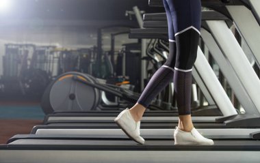 Slim Fitness kadınının beyaz ayakkabıları Fit Gym 'de koşu bandında ısınıyor. Kavramsal kadın sporcu olabilir. Sağlıklı, kopyalama alanı.